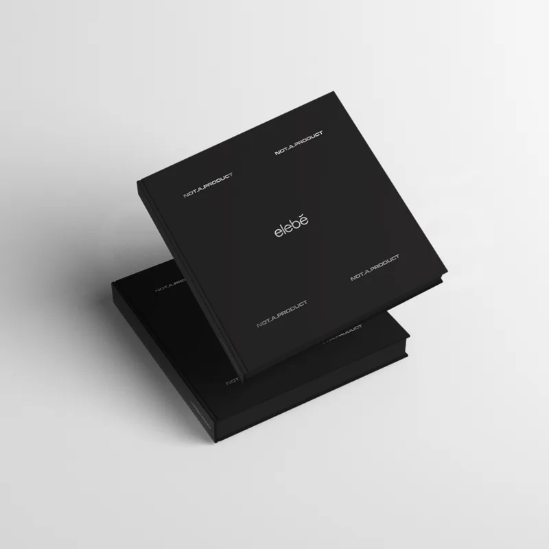 Two square black cases stacked at an angle, the elebe wordmark centred and NOT.A.PRODUCT repeated across the lid.