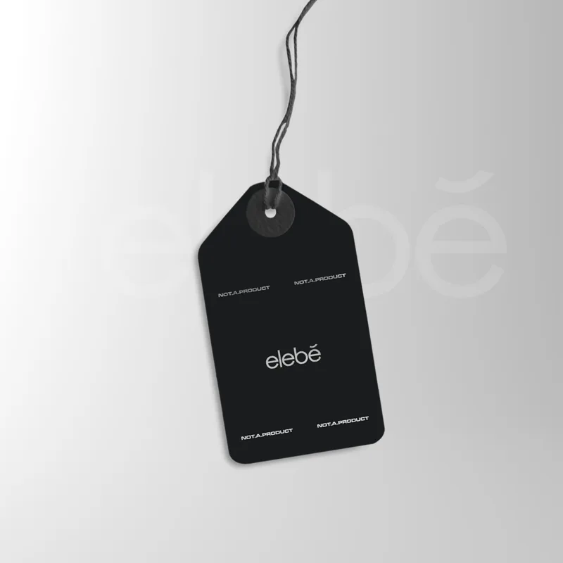 A black hang tag on a twisted cord, the elebe wordmark centred and NOT.A.PRODUCT set at each corner.