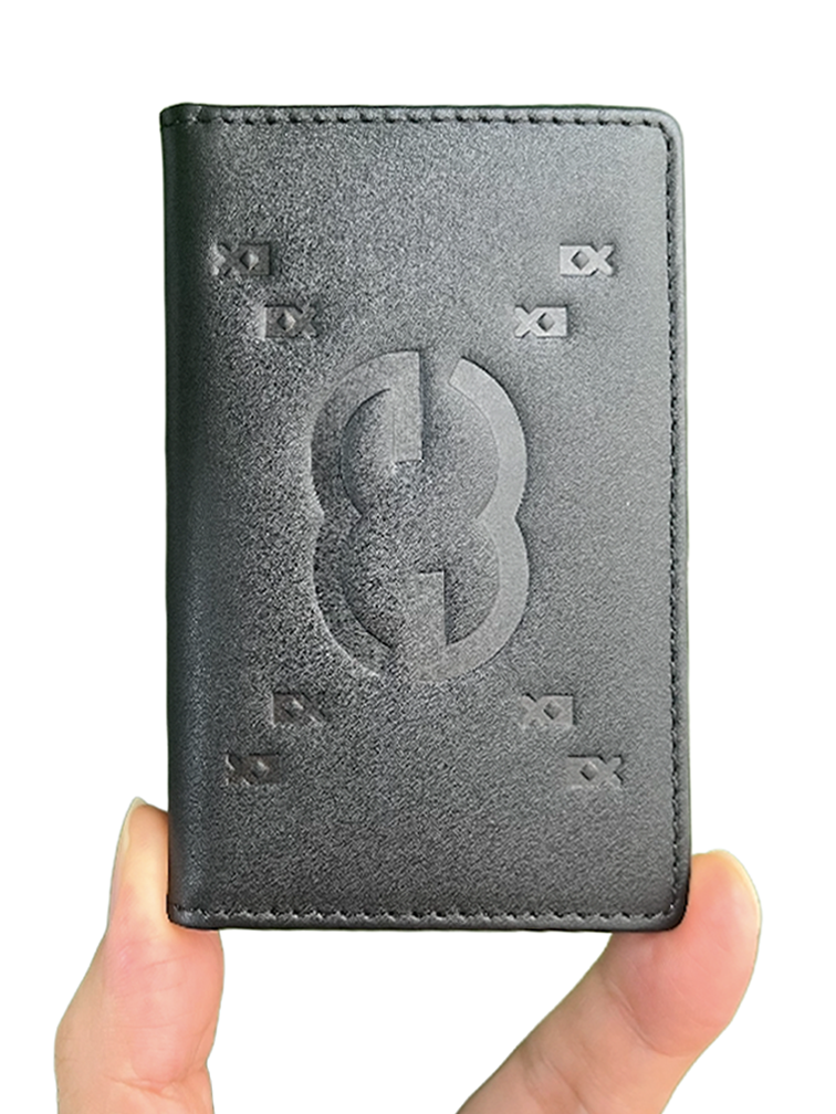 Two full-grain leather card wallets held in one hand, blind-embossed with the elebe mark.